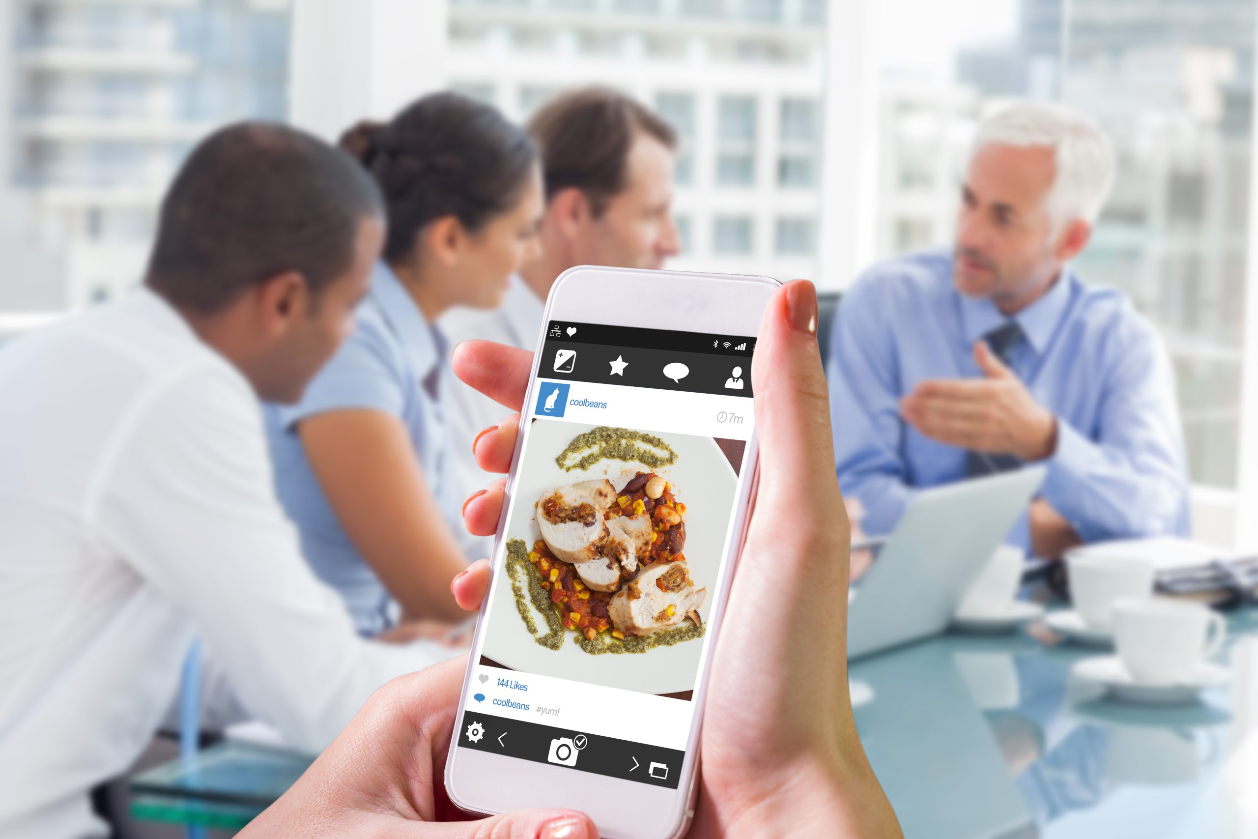 Hand holding smartphone against overhead view of delicious chicken dish with salsa